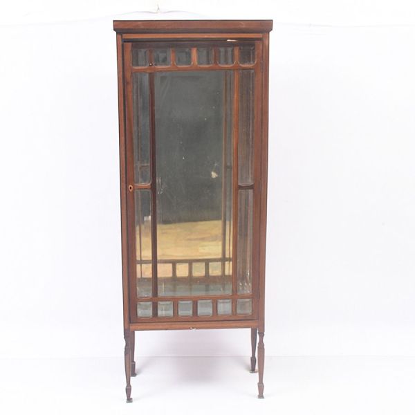 Vitrine inglesa Eduardiana de porta única, em madeira nobre de linhas retas e elegantes, sobre pernas afuniladas e retas, terminadas em pés cônicos com sapatas de metal. Corpo envidraçado em quase tod