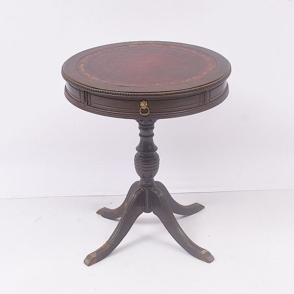Mesa auxiliar (drum table) estilo inglês vitoriano com inspiração regência. Executada em madeira nobre entalhada com tampo revestido em couro gravado com motivos florais e vegetalistas. A borda do tam