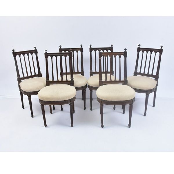 Conjunto composto por doze cadeiras em madeira nobre entalhada, no estilo Luís XVI. Espaldar vazado com montantes verticais estriados (colunelos), encimado por travessa horizontal ladeada por florões