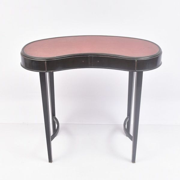 Mesa em formato de `rim` (kidney-shaped), em madeira laqueada em preto, com tampo revestido em couro em tom marrom/bordô. A linha é elegante e curva, com quatro pernas finas e retas (estilo neoclássic