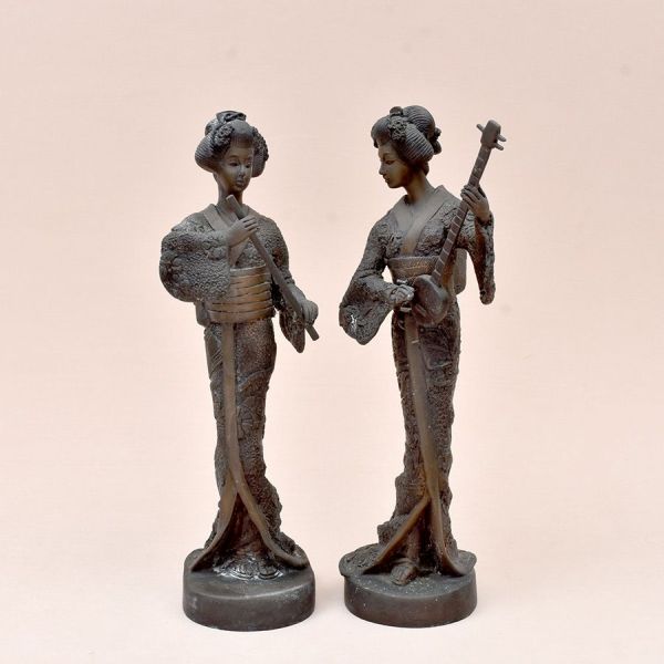 Par de esculturas japonesas em bronze representando gueixas em pé, trajando quimono ricamente texturizado com motivos florais em relevo baixo, faixa obi larga amarrada à cintura e penteado tradicional