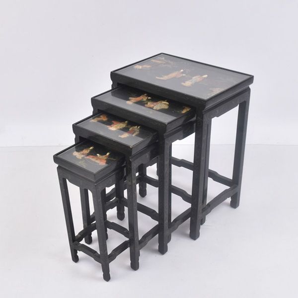Conjunto de quatro mesas ninho encaixantes (nesting tables). Estrutura em madeira preta, pernas retas. Cada tampo é protegido por vidro e traz composição decorativa distinta, representando paisagens d