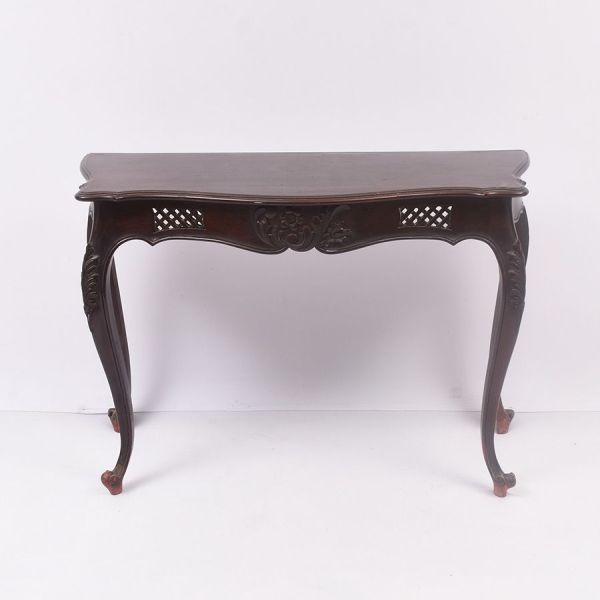 Console estilo Luís XV, em madeira entalhada, com tampo de linhas serpenteadas e pátina natural. Cinta frontal ricamente trabalhada com motivos florais em relevo, intercalados por painéis vazados em t