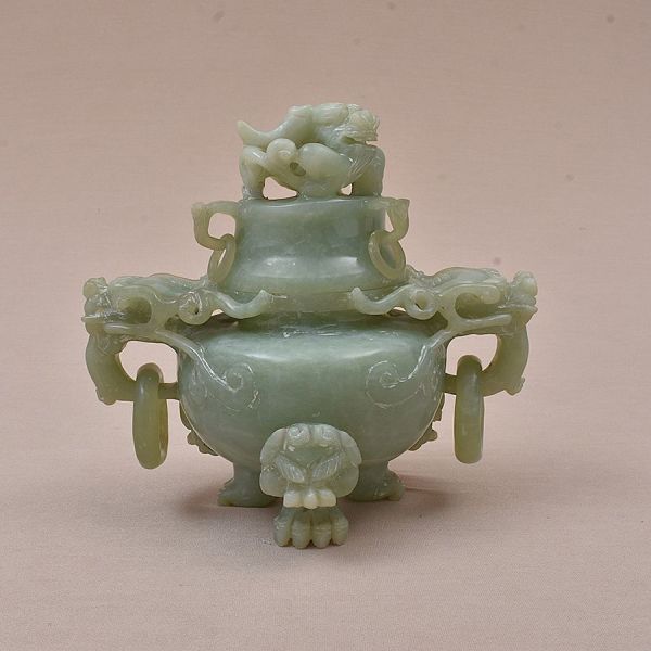 Escultura em jade do sec. XIX verde entalhada representando um vaso ritual tripé (ding) com tampa e alças em forma de dragão. Corpo bulboso sobre três pés zoomórficos, alças vazadas com cabeça de drag