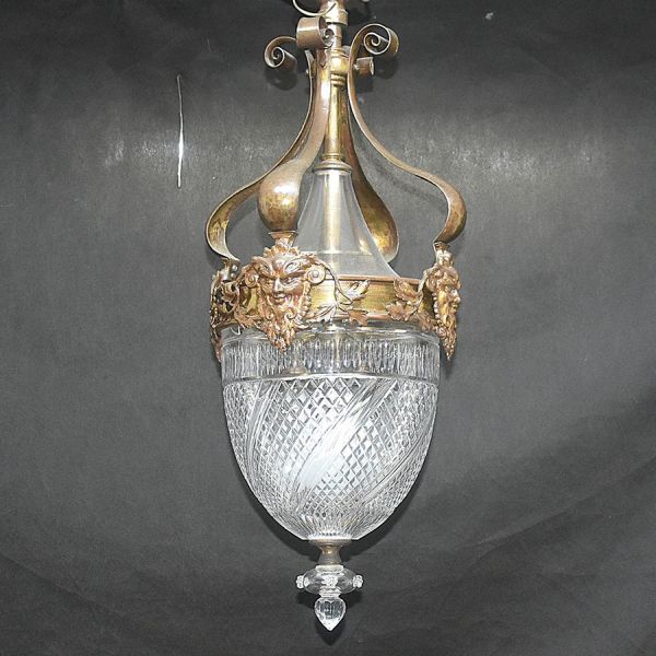 Lustre em cristal lapidado com motivos de losangos e facetas em talha diamante, formato de campânula com pingente central e remate em gota facetada na base. Estrutura de sustentação em bronze com braç