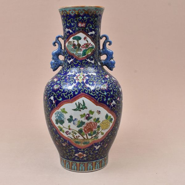 Vaso em porcelana chinesa fundo azul-cobalto, corpo balaústre com gargalo alto e boca evasê, guarnecido por par de alças modeladas em forma de dragões estilizados esmaltados em azul. Superfície inteir