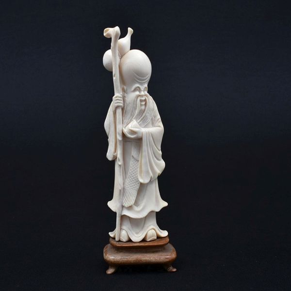 Estatueta de marfim chinês cerca de 1940 representando Shou Xing, o deus da Longevidade. Segura o pêssego e traz o cajado feito de também ramos de pessegueiro representam a divindade da Longevidade e