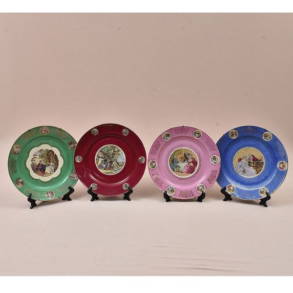 Conjunto de quatro pratos decorativos de porcelana, germânico, com cenas galantes e pastoris ao centro emolduradas em reserva branca, e cercadura em cores contrastantes (azul, rosa, verde e bordô) orn