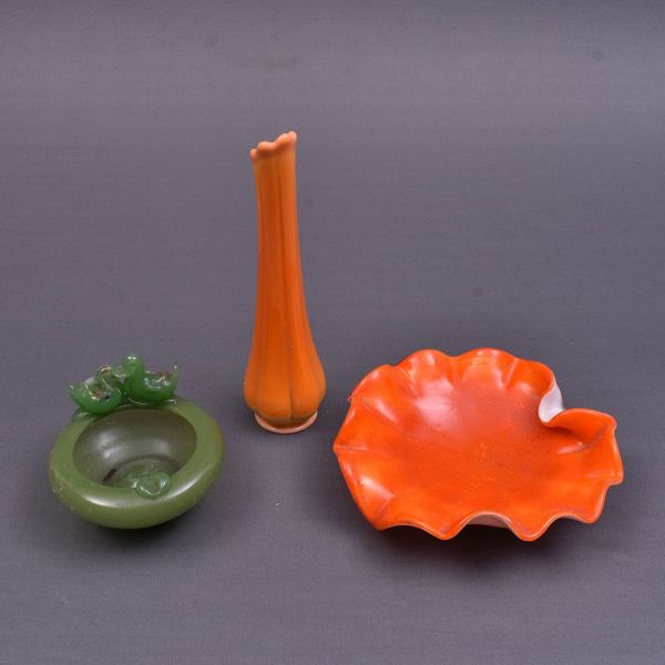 Três peças de vidro opalinado, sendo dois cinzeiros, um na cor verde e outro laranja moldados e a terceira peça é um vaso unifleur em tom alaranjado. Alt. 25 cm e diam. 20 e 13 cm. O cinzeiro verde ap