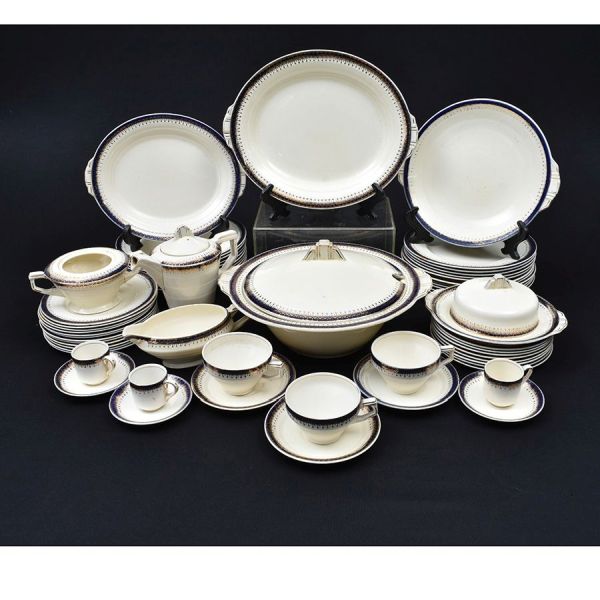 Aparelho de porcelana tcheco na cor creme com frisos azul e dourado. Composto de 11 pratos rasos, 9 fundos, 20 de sobremesa, 1 sopeira, 1 molheira, 2 travessas ovais, bule de café, 3 xícaras com pires