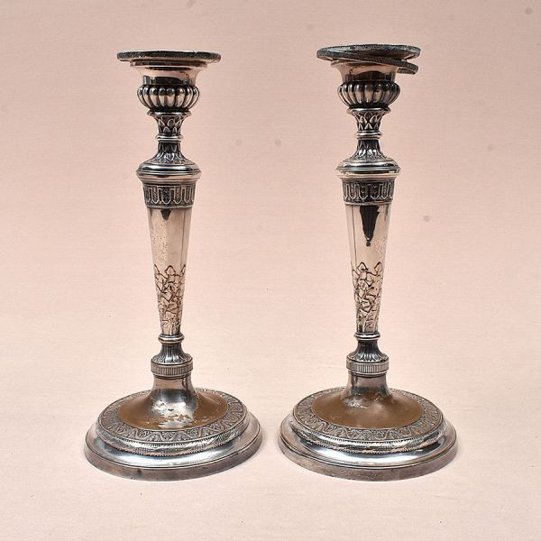 Par de castiçais franceses em metal prateado, de elegante desenho neoclássico, apresentando fuste torneado e afunilado, enriquecido por delicados motivos florais Bases circulares escalonadas. Alt. 33