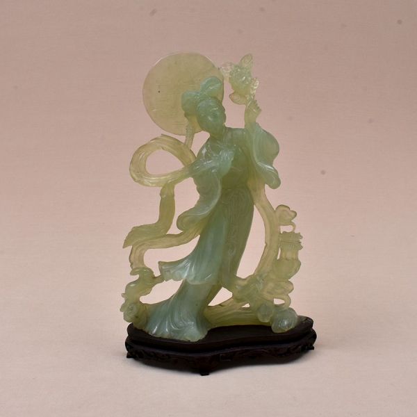 Escultura chinesa do sec. XIX em jade verde entalhada — dama com leque, trajando vestes fluidas com longas faixas ondulantes, penteado ornamentado, segurando ramo florido. Alt. 30 cm. Base em madeira