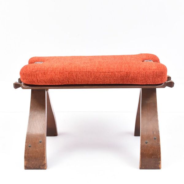 Banqueta de apoio (tipo mocho) em madeira, com assento retangular de tampo liso e pernas em `X` recortadas, unidas por travessa central. Estofado avulso em chenille terracota. Med. 45 x 65 x 30 cm (A
