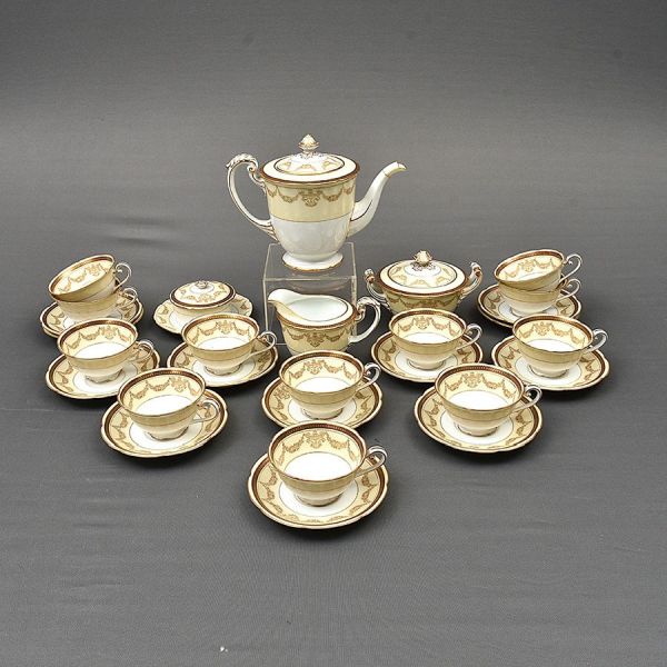 Aparelho de chá de porcelana japonesa Noritake na cor creme com guirlanda floral em dourado. Composto de bule de chá, açucareiro, 1 manteigueira, 1 cremeira e 12 xícaras com pires de chá.<br>Total 28