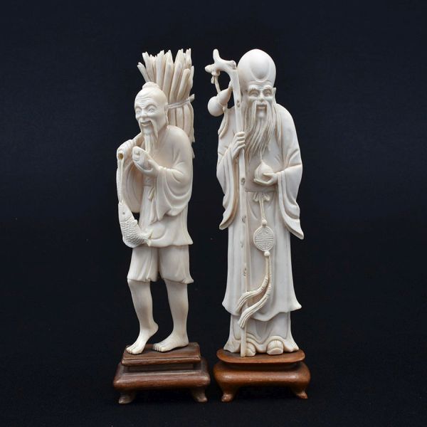 Duas estatuetas de marfim chinês cerca de 1940, uma representando Shou Xing, o deus da Longevidade e um pescador. Bases de madeira. Alt. total 20 cm. No pescador a vara está com pequeno quebradinho.