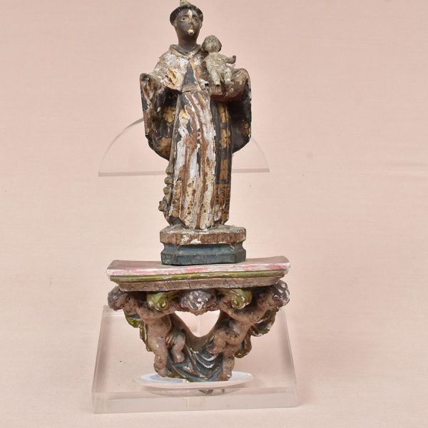 Imagem brasileira do sec. XIX em madeira policromada representando Santo Antônio sobre pedestal com duas figuras de querubins. Alt. total 33 cm. Ausência de uma mão da imagem e mão e pés do menino.