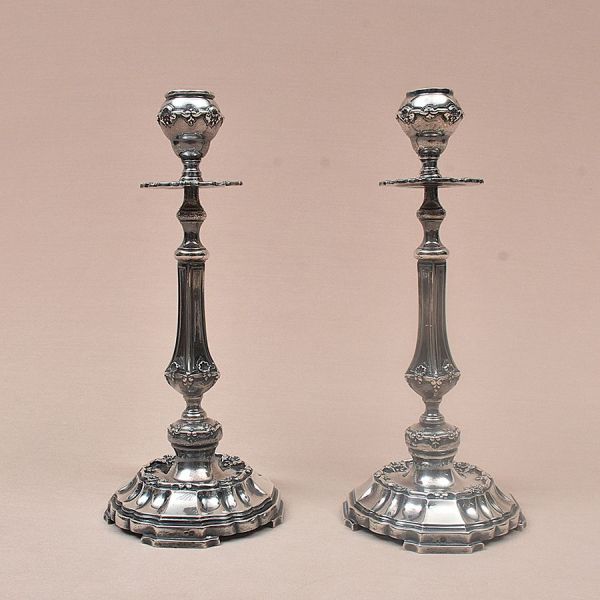 Par de castiçais de prata portuguesa contraste Águia com punção de garantia de teor 916 milésimos prateiro Topázio. Bojo com delicado cinzel de palma sobre duas volutas. Alt. 27 cm. Peso: 995g.