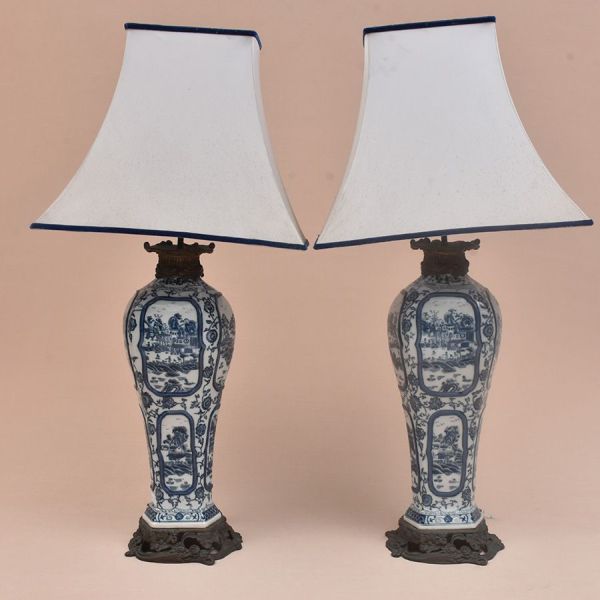 Par de luminárias de porcelana chinesa azul e branca decorada em reservas com cena de paisagem sobre fundo floral e guarnecida por bronze cinzelado com flores. Alt. 50 cm e alt. total 82 cm.