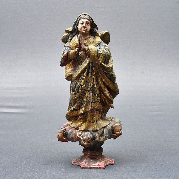 Brasil – sec. XIX. Imagem de madeira representando Nossa Senhora da Conceição. Apresenta-se com as mãos unidas em ração e vestes em douração. Base com três cabeças de querubins. Alt. 34 cm.
