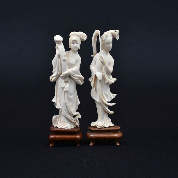Par de estatuetas de marfim chinês cerca de 1940 representado figuras de damas. Base de madeira. Alt. total 18 e 17 cm. Uma delas com dois pequeninos restauro na mão e no adereço da mão.