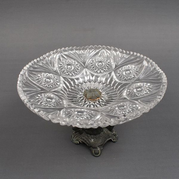 Centro de mesa europeu em fer forge e cristal. Base moldada com figuras de crianças ladeando um vaso floral. Prato de cristal lapidado em elementos geométricos. Alt. 21 e diam. 34 cm.