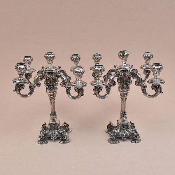 Par de candelabros para cinco velas de prata portuguesa contraste Águia com punção de garantia de teor 833 milésimos. Todo cinzelado com palmas e volutas. Alt. 34 cm. Peso: 5.180g.