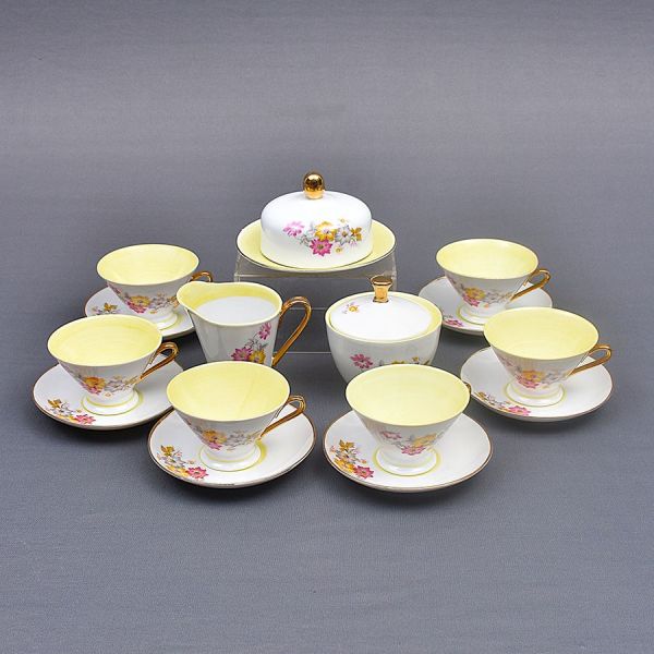 Aparelho de chá de porcelana alemã da Bohemia, decoração floral com interior em amarelo e detalhes em douração. Composto de leiteira, manteigueira, açucareiro e 6 xícaras com pires