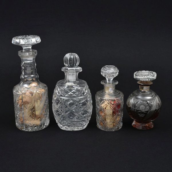 Quatro garrafas europeias diversas de cristal translúcidas de diferentes lapidações e tamanhos. Alt. 29,25, 20 e 18 cm. A de tamanho 20 cm apresenta um bicadinho na base.