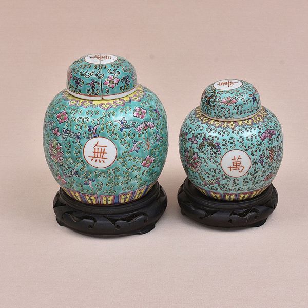 Dois potiches de porcelana chinesa decorado com flores policromadas sobre fundo verde. Alt. sem base 15 e 12 cm. O maior apresenta trincado na parte interna da tampa.