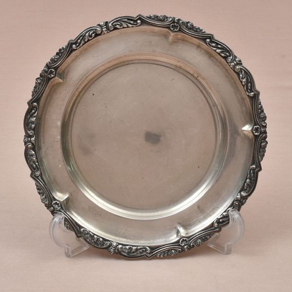 Salva de prata portuguesa contraste Águia com punção de garantia de teor 833 milésimos. Centro liso e borda cinzelada com flores e volutas. Diam. 25 cm. Peso: 530g.