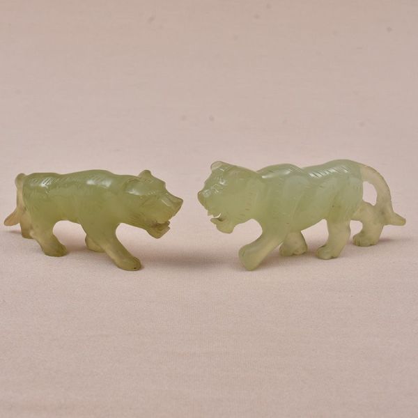 Duas esculturas chinesas do sec. XIX em jade verde entalhada representando leões. Um deles com pequenino quebradinho na ponta do rabo. Alt. 4 e comp. 10 cm.