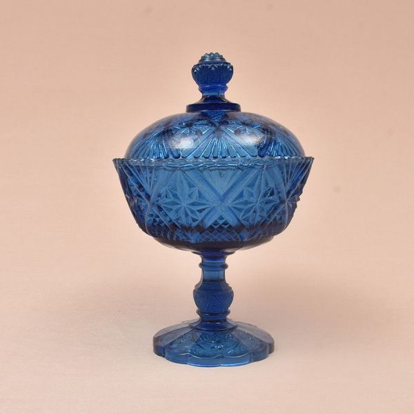 Compoteira de grosso cristal na cor azul toda lapidada em elementos geométricos. Alt. 25 cm. Imperceptível bicadinho na parte interna da tampa e na borda
