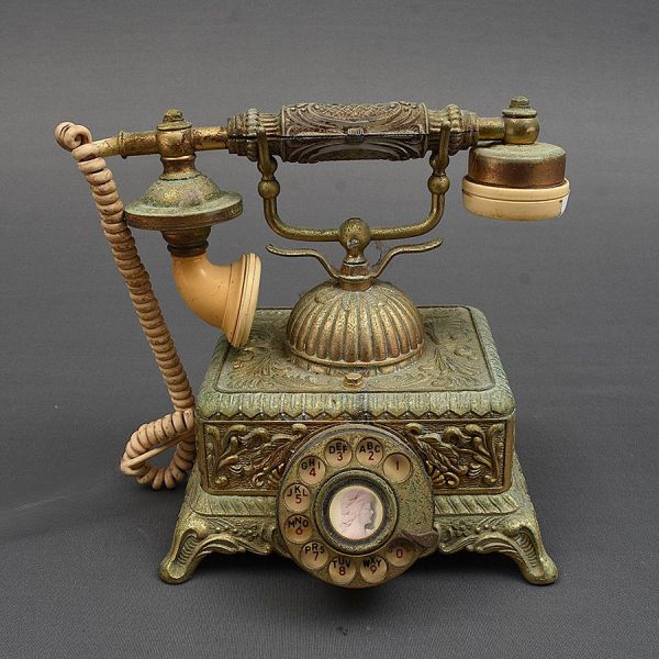 Telefone europeu em metal dourado ricamente decorado em cinzel de palmas e acantos. O fone com acabamento em marfinite. Med. 24 x 21 x 20 cm (A x L x P)