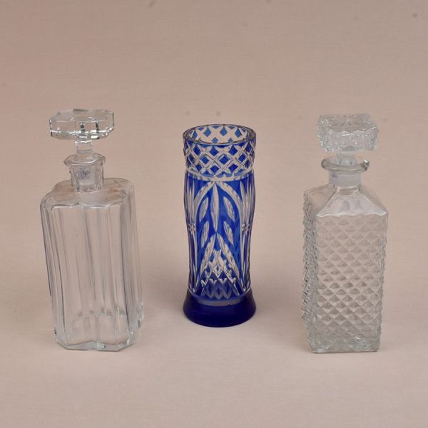 Três peças de cristal: Vaso lapidado em overlay azul e duas garrafas quadrangulares, uma com lapidação bico de jaca e outra moldada. Alt. 26, 25 e 22 cm.