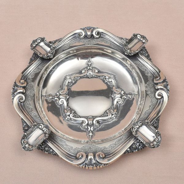 Cinzeiro de prata portuguesa contraste Águia 1 título com punção de garantia de teor 915 milésimos. Decoração em volutas. Med. 22 x 22 cm. Peso: 305g.
