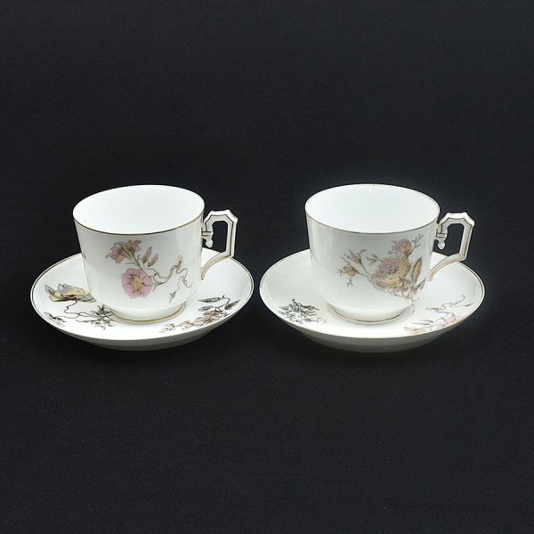 Par de grandes xícaras com pires de porcelana francesa decoradas com flores em policromia. Uma delas com fio de cabelo. Alt. 9 cm e diam . pires 18 cm.