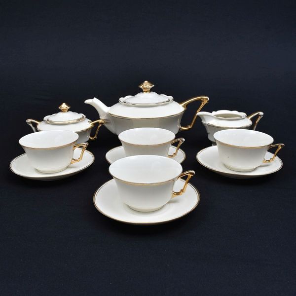 Aparelho de porcelana tcheca na cor creme com friso dourado. Composto de Bule de chá, açucareiro, cremeira e 4 xícaras com pires de chá. Total 11 peças
