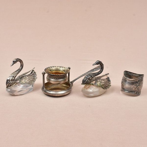 Três peças de prata europeia: Dois saleiros em formato de cisne e um coador de chá. Acompanha um porta guardanapo de metal prateado. Peso da prata 90g.