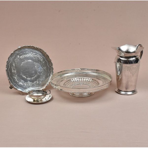 Quatro peças prateadas de diferentes procedências: Jarra, xícara com pires (ausência do fundo), e duas salvas. Diam. 30 e 24 cm e alt. jarra 22 cm.