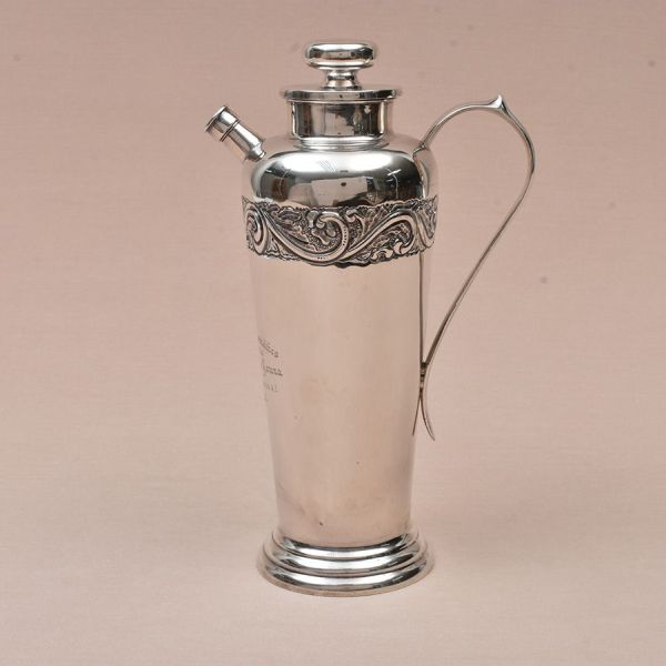 Refresqueira de prata mexicana com punção de garantia de teor 900 milésimos. Bojo liso com detalhe decorativo em acantos. Alt. 32 cm. Peso: 1.070g.