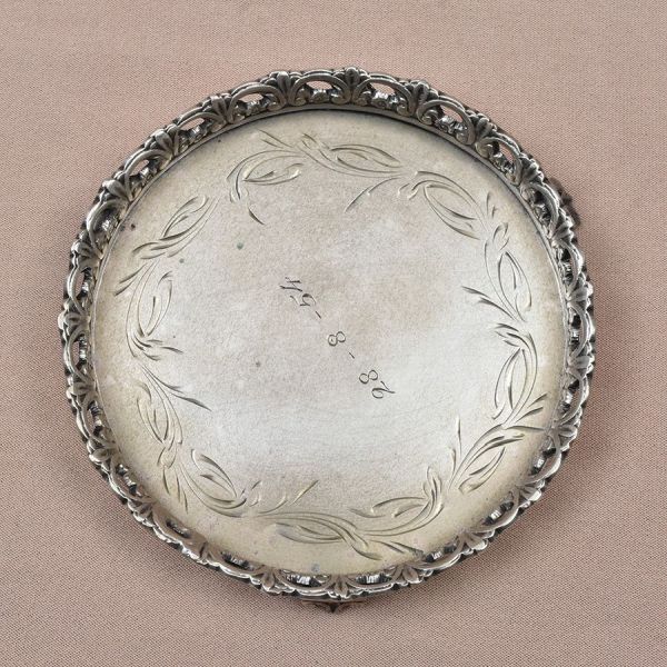 Mini salva de prata brasileira com punção de garantia de teor 833 milésimos. Lavrada e cinzelada. Diam. 9 cm. Peso: 105g. Ausência de um pezinho.