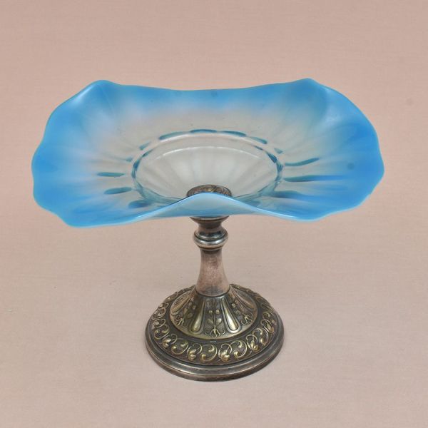 WMF. Fruteira alemã cerca de 1900 com base prateada e cinzelada com flores. Recipiente em vidro opalinado na cor azul. Alt. 22 cm e diam. 28 cm.