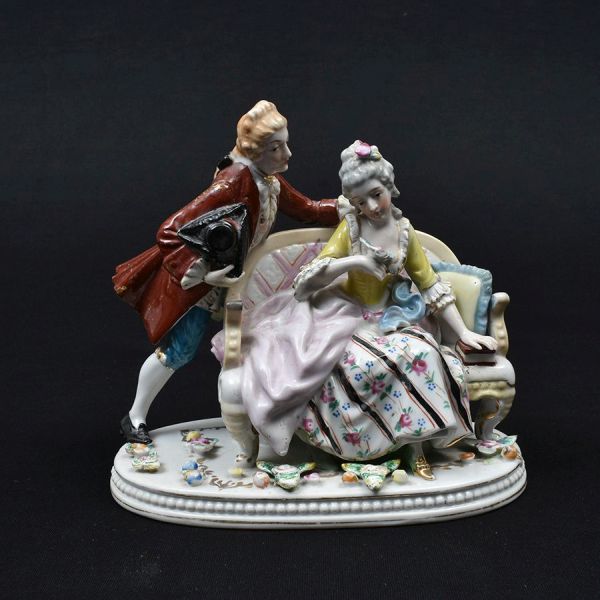 Grupo escultórico de porcelana europeia representando cena de galanteio em policromia. Fio de cabelo na base. Med. 19 x 20 x 12 cm (A x L x P)