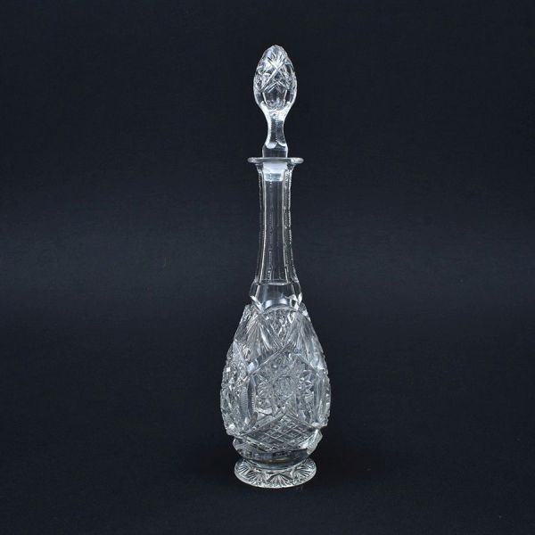 Garrafa de cristal europeu ricamente lapidada com elementos geométricos. Apresenta pequenos bicadinhos na base. Alt. 44 cm. Tampa adaptada.