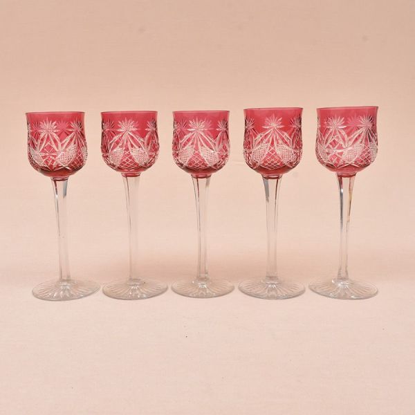 Baccarat. Cinco taças de cristal rubi lapidadas com elementos geométricos. Haste translúcida e facetada e base estrelada. Alt. 21 cm.