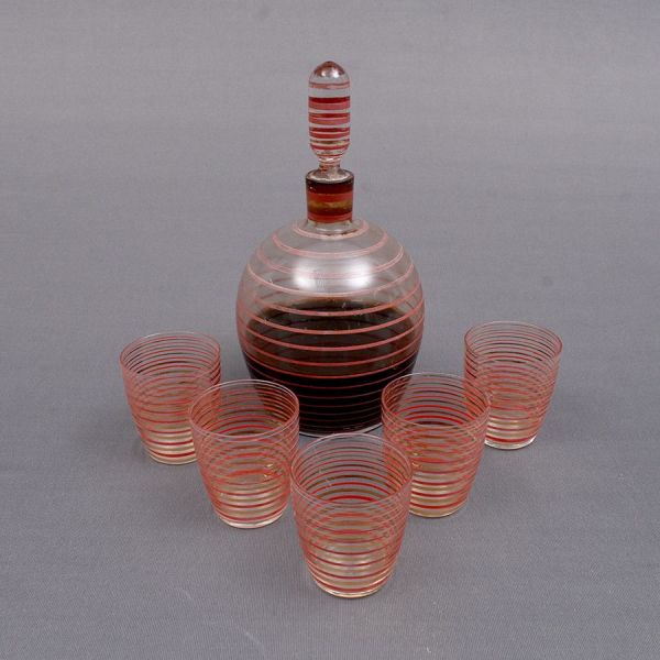 Licoreira com 5 copos de cristal italiano translúcido decorado com frisos em tom de vermelho e dourado intercalados. Alt. 21 e 6 cm.