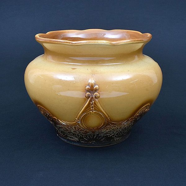 Cachepot de faiança na cor ocre alaranjado decorado na parte inferior com flores. Alt. 20 cm e diam. 21 cm. Pequeno bicado na base.