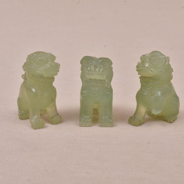 Três esculturas chinesa do sec. XIX em jade verde entalhada representando cães de fó. Um deles com ausência de uma pata. Alt. 5 cm.