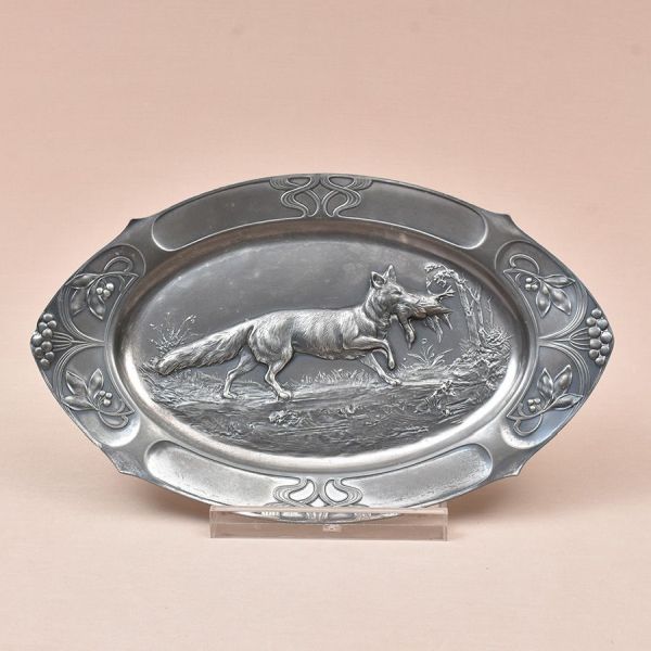 WMF. Travessa Art Nouveau prateada decorada em relevo com figura de raposa com sua presa. Borda com folhagens. Med. 28 x 46 cm.