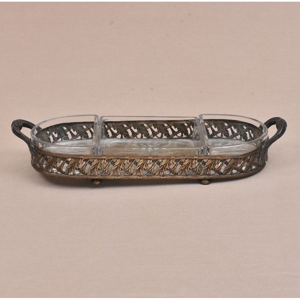 Petisqueira prateada trabalhada em motivos vegetativos. Três recipientes de cristal. Med. 34 x 11 cm. Ausência de um pezinho.